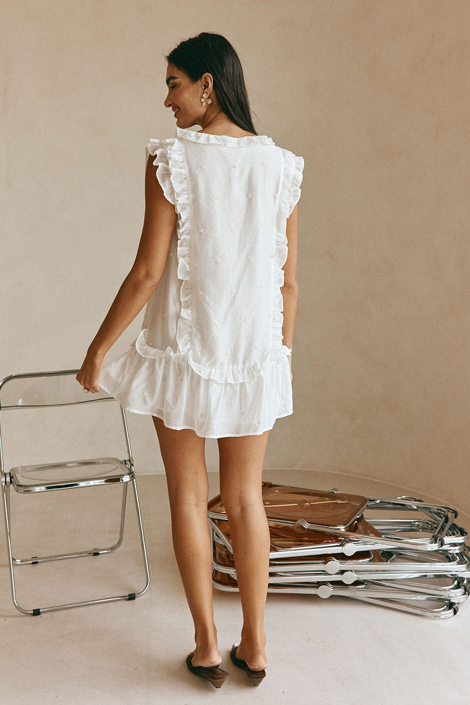 White mini dress with a V neckline, styled on model